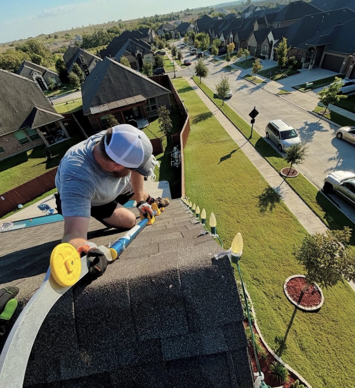 Installer clipping C9 bulbs along a gutter line