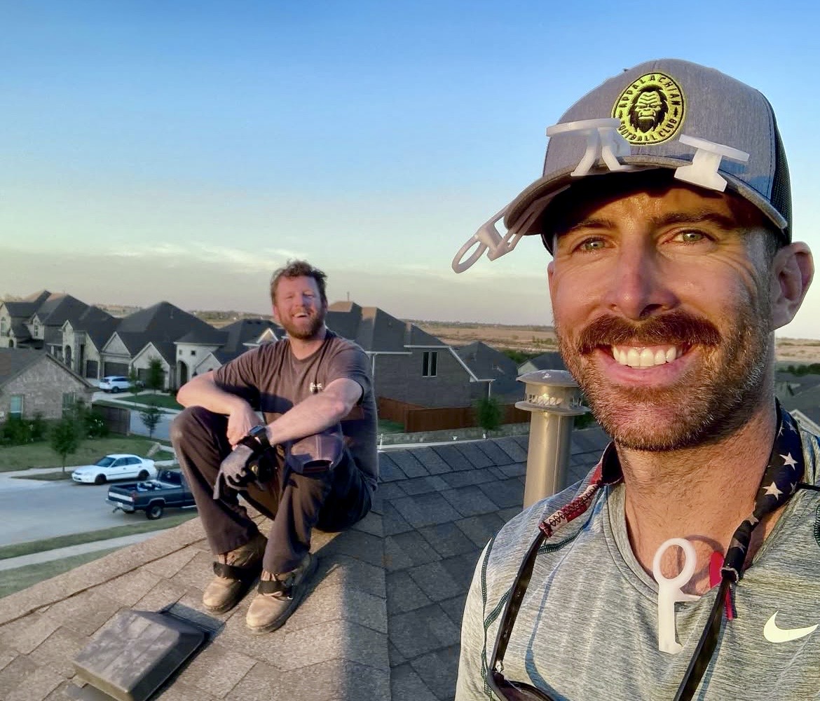 Two Jolly Icicles installers on a rooftop at sunset